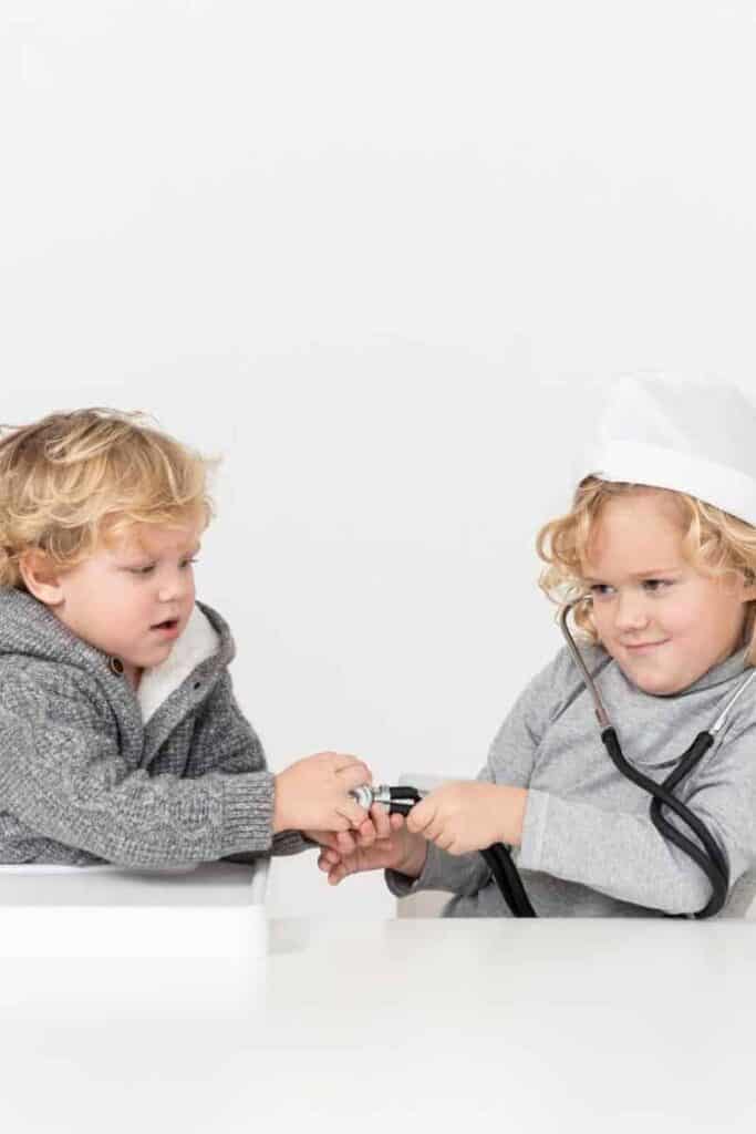 Two toddler playing doctor together and having a good time.