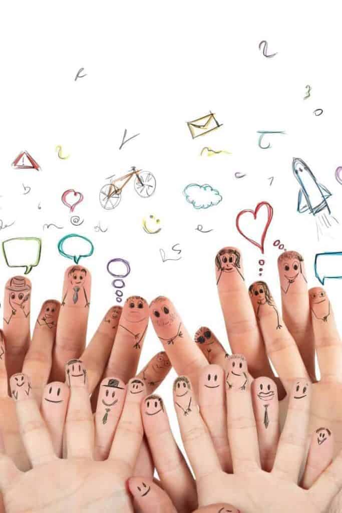 A few sets of hands adults and kids with family and stick faces drawn on the finger tips representing social togetherness and learning in children. 