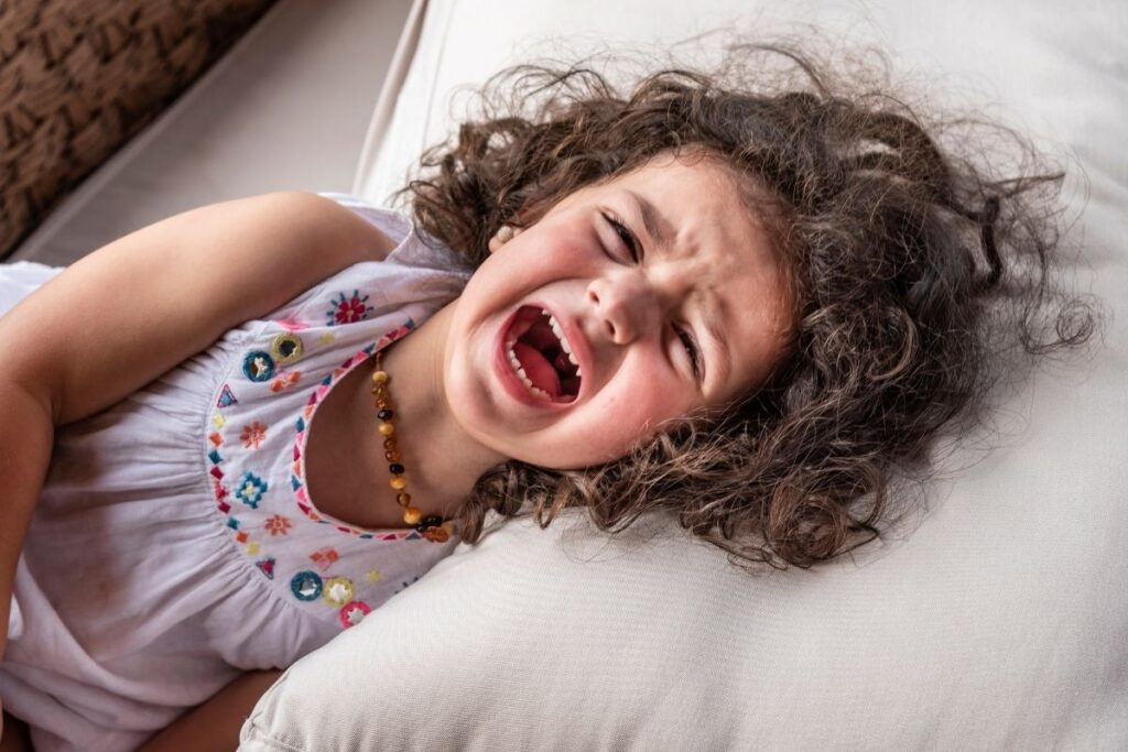 Curly brown-haired toddler throwing a tantrum.