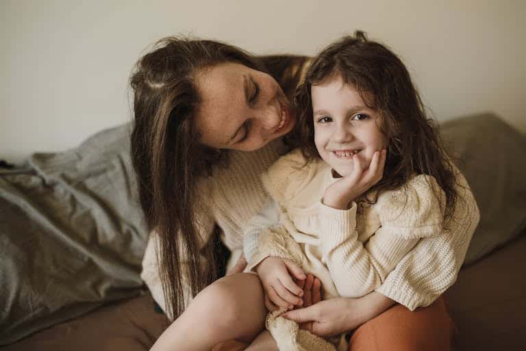 A tender moment between a mother and her daughter, smiling and enjoying their time together indoors.