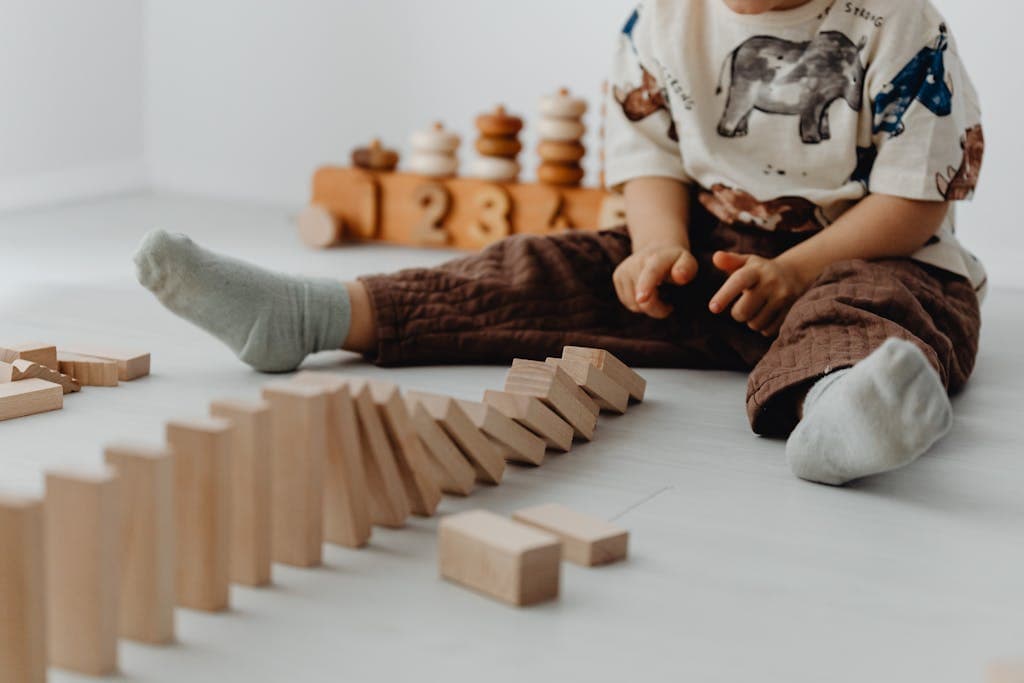 A young child playing with wooden blocks on a light floor, creating a playful and educational scene.