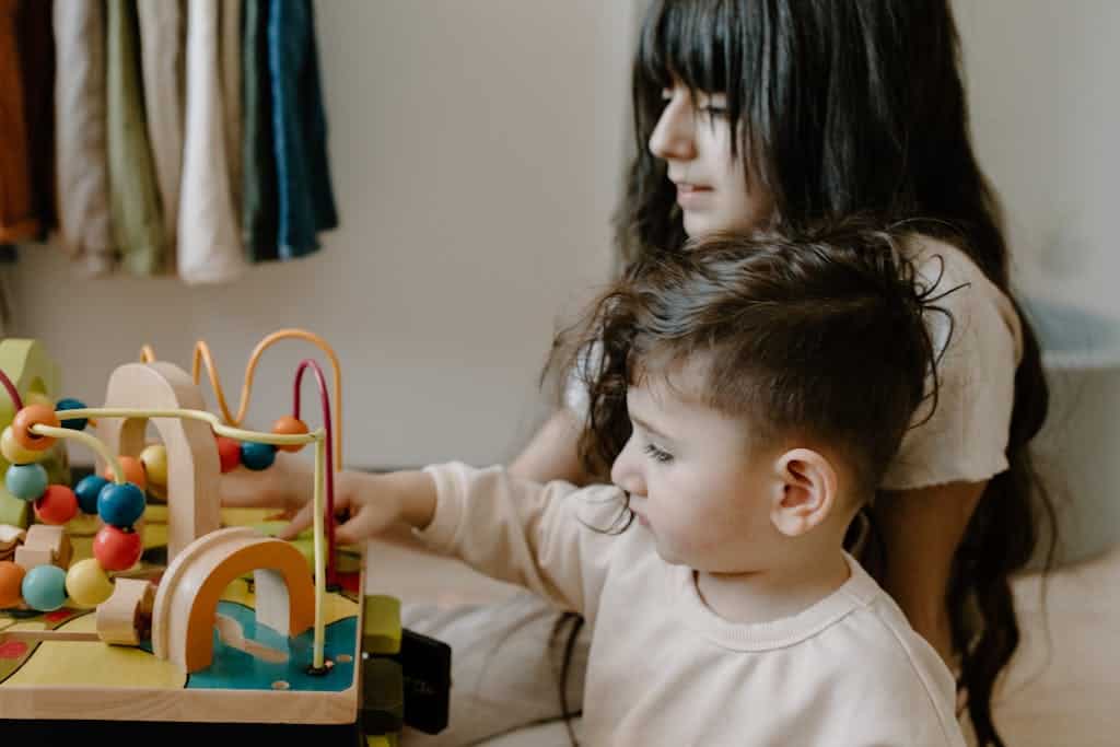 Two children engaged with wooden toys at a table, fostering imagination and playtime.