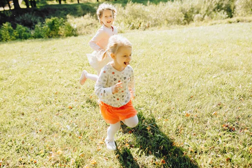 Two young girls laughing and playing on a sunny day in the park.